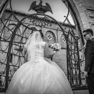 Fekete-fehér esküvői pillanatkép, a templom előttt, mennyasszonyi virágcsokorral, napszemüveggel